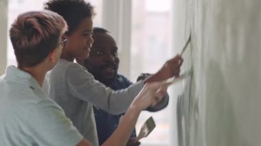 Neşeli Kafkasyalı anne, Afro-Amerikalı baba ve küçük melez oğul gülümsüyor, konuşuyor ve duvarları boyuyor.