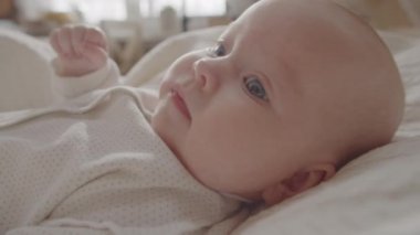 Kafkasyalı yeni doğmuş şirin bir bebeğin evde yatakta yatarken yakın plan çekimi.