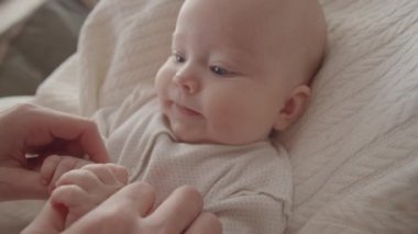 Beşikte yatıp annesine bakan, 3 aylık, güzel, uykulu bir kızın fotoğrafını çek.