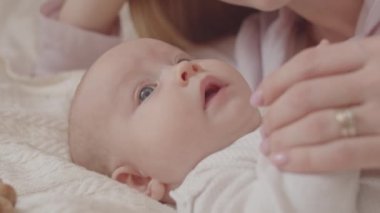 Sevecen annenin, evde birlikte yatarken tatlı kızını nazikçe okşayıp öptüğü yakın çekim.