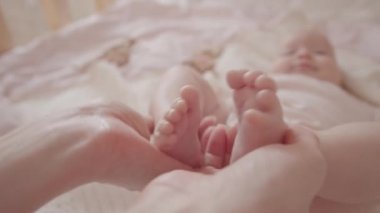 Annenin küçük şirin yeni doğmuş bebeğinin küçük ayaklarını tutarken çekilen seçici odak fotoğrafını kapat.