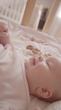 Sevimli annesinin minik ayaklarını öperken beşiğinde yatan 3 aylık sevimli kızın dikey yakın çekimi.