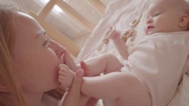 Hollanda açısı, tatlı bir kızın beşiğinde yatarken annesinin ayaklarını öptüğünü gösteriyor.