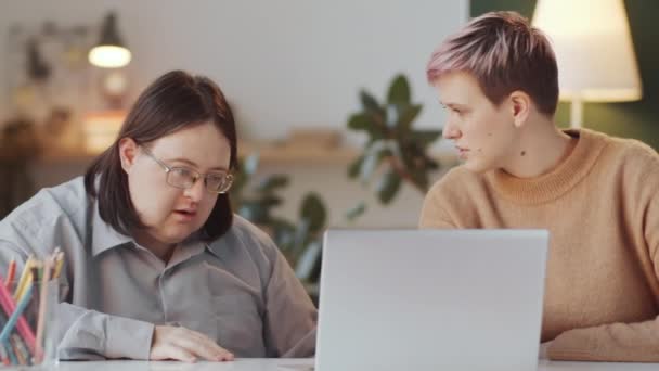 ダウン症の成人男性を教える女性ソーシャルワーカー自宅でラップトップを使用する方法 — ストック動画