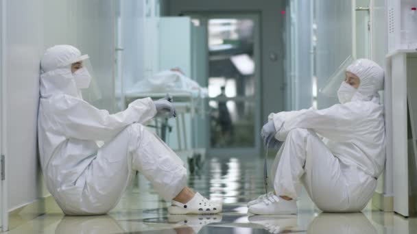 Two Female Doctors Protective Suits Face Shields Masks Gloves Sitting — Stock Video
