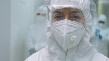 Korunma giysisi giymiş kadın doktor portresi, yüz kalkanı ve maskesi hastanede duruyor ve koronavirüs salgını sırasında kameraya bakıyor.