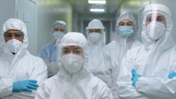 身着防护服 口罩和手套的多族裔男医生和女医生组成的小组在科罗纳韦病毒大流行的工作日站在医院里拍照 — 图库视频影像