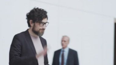 Orta yaşlı, beyaz bir adamın göğüs göğüse çekilmiş fotoğrafı havaalanında bekleme salonunda, takım elbiseli Afro-Amerikan arkadaşıyla buluşuyor, el sallıyor, gülümsüyor, kocaman sarılma hareketleriyle selamlıyor, konuşuyor ve uzaklaşıyor.