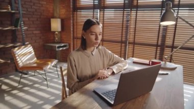 Genç ve çekici bir iş kadınının ofis masasındaki bilgisayardan iş görüşmeleri ve el sallamaları.