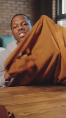 Genç Afro-Amerikalı adamın kazak giydiğini gösteren ve moda sosyal medya kanalı için video kaydederken kamerada anlattığı dikey bir fotoğraf.