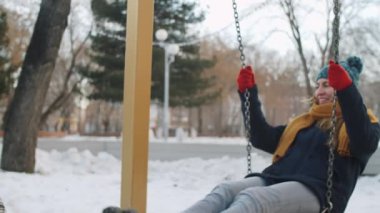 Neşeli genç beyaz kadın salıncakta sallanıyor, gülümsüyor ve felçli Afro-Amerikan bir adamla sohbet ediyor kış günü parkta yürürken.