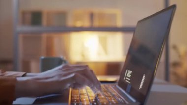 Tanımlanamayan bir kadının ellerinin gece geç saatlere kadar masa başında oturmasının, dizüstü bilgisayar kodlarını klavyeye yazmasının ve ekranda çalışan dijital sembollerin yakın plan çekimleri.