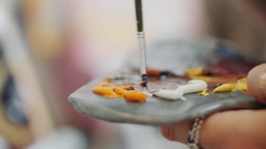 Resim yapmak için yeni bir renk yaratırken yağlı boyaları palette karıştıran tanınmayan ressamın görüntüsünü kapat