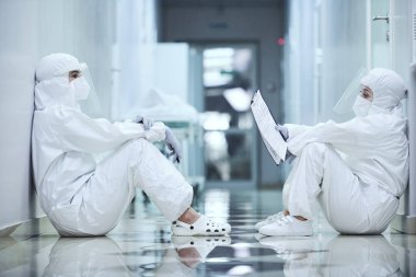 Hastane koridorunda oturan cerrahlar.