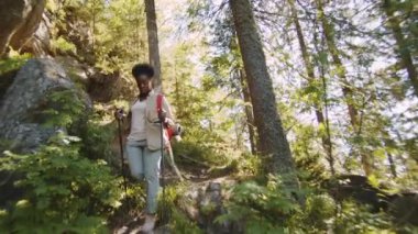 Yaz günü dağ ormanlarında yürüyüş yaparken kayalık patikada yürüyen Afro-Amerikalı kadın turistin alçak açılı görüntüsü.