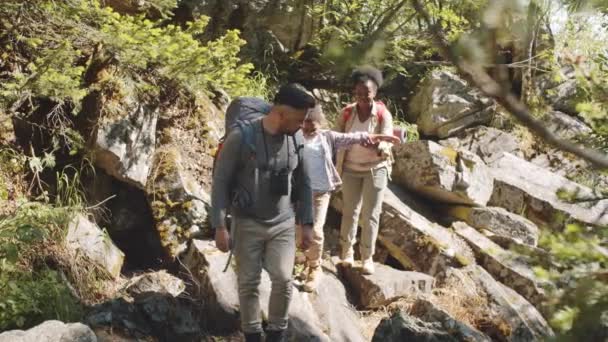 Padres Multiétnicos Hijo Pequeño Caminando Con Mochilas Sendero Rocoso Mientras — Vídeo de stock