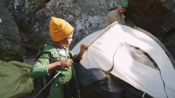 一个混血的小男孩帮助白人父亲搭起帐篷 同时在山林里一起准备营地 — 图库视频影像