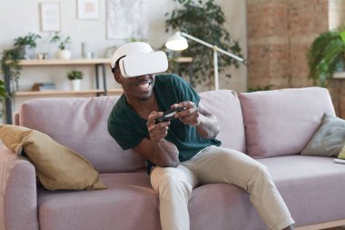 Adam kanepede oturup oyun oynarken eğleniyor.