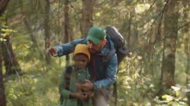 Kafkas babası ve küçük melez oğlu ormanda yürürken akıllı telefondan navigasyon uygulaması kullanıyorlar.