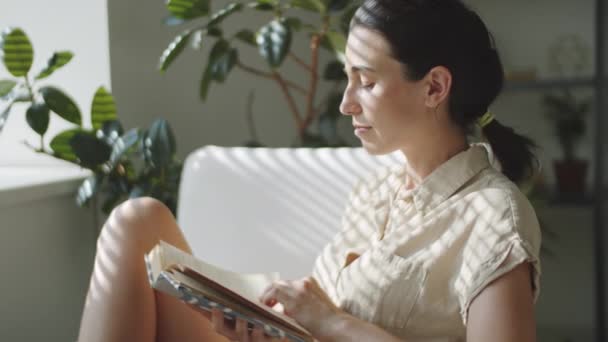Junge Schöne Frau Sitzt Hause Sessel Liest Ein Buch Und — Stockvideo