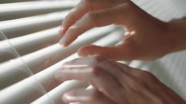 Evde kadın elinin yatay pencere perdelerini açtığı Hollanda açılı çekimleri kapat