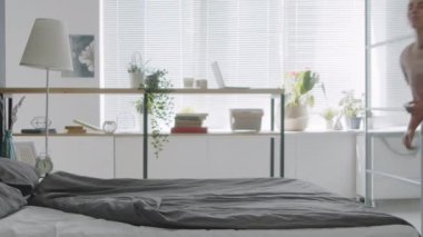 Yavaş çekim, pijamalı genç bir kadın gözleri kapalı yatağa atlıyor ve karnının üstünde uyuyor.