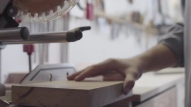 Uzman atölyesinde testereyle kereste boşluğundan ince odun parçaları kesen tanınmamış erkek marangozun yakından çekilmiş görüntüleri.