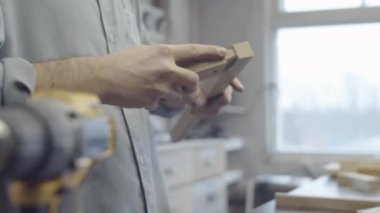 İsimsiz erkek marangozun ahşap mobilya bileşenlerini birleştirirken, ahşap ve tenon eklemli ve atölyeye bastırırken yakın plan çekli fotoğrafları.