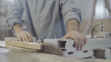 Anonim marangozun yakın plan çekimleri ahşabı kenetlenmiş bir şekilde tahta parçasıyla kenetlenmiş, ahşap testeresi ile ahşap atölyesinde, etrafta uçuşan talaşlarla