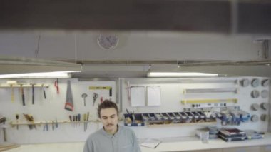 Erkek marangozun üç bacaklı ahşap tabana mermer desenli dekoratif masa üstünü denerken ve mobilya atölyesinde kumaşla tozunu alırken,