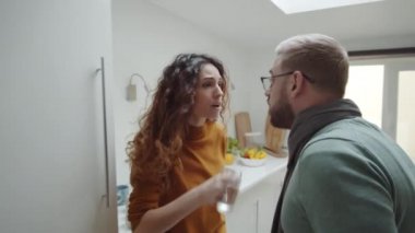 Güzel beyaz bir kadının su içerken erkek arkadaşıyla kavga ederken, onunla alay ederken, yatak odasına hışımla giderken ve kapıyı çarparken orta ölçekli bir görüntüsü.