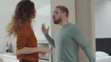 Evli, beyaz bir çiftin evde patlayıcı kavgası, kızgın bir adamın karısına ve öfkeli bir kadına bağırması, sonra da bir bardak su alıp içki içmesi.