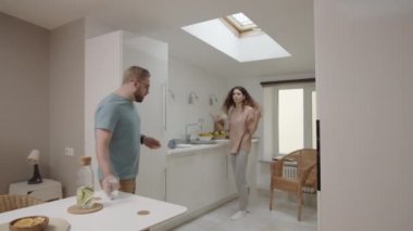 Genç, beyaz bir kadının mutfakta bulaşık yıkarken, şikâyet ederken, tembel erkek arkadaşı azarlarken, tabak kırarken ve havluyla döverken, ve bir adam ona su fırlatırken.