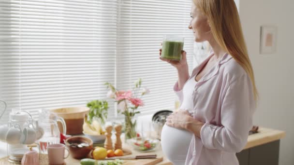 Neşeli Hamile Bir Kadının Elini Karnına Koyup Evde Yeşil Smoothie — Stok video