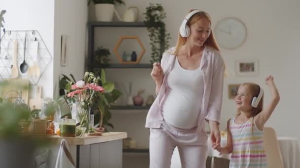Wesoła Kobieta Ciąży Jej Córeczka Słuchają Muzyki Słuchawkach Bezprzewodowych Trzymają — Wideo stockowe