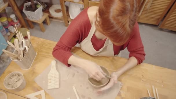 Stüdyoda Masada Oturan Kızıl Saçlı Kadın Çömlekçi Ahşap Kaburga Aletli — Stok video