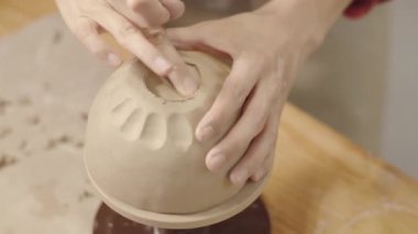 Kimliği belirsiz kadın çömlekçinin el yapımı sert, dairesel parmak hareketleriyle deri, el yapımı kil damarın kenarlarını düzleştirirken yakın plan çekimleri.