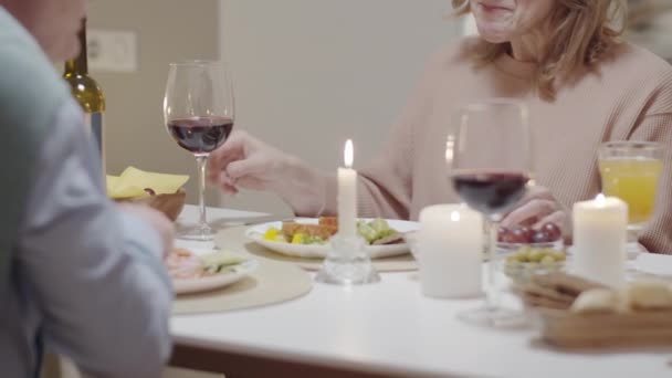 大人のカップルがおいしい食事を食べ ワインやキャンドルとテーブルに座っている間にチャットし 自宅でロマンチックなディナーを楽しむのミッドセクションショット — ストック動画