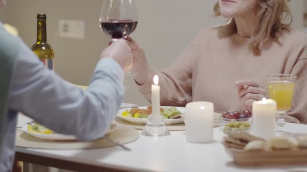 食事やろうそくとテーブルに座っている間 成熟した男性と女性の眼鏡をかけ 赤ワインを飲むと自宅でロマンチックなディナーを持っている — ストック動画