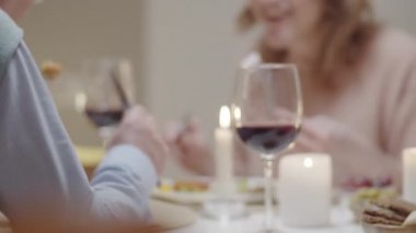 Masada şarap ve mumlarla romantik bir akşam yemeği yerken aile üyelerinin yemek yiyip konuştuğu görüntüler.