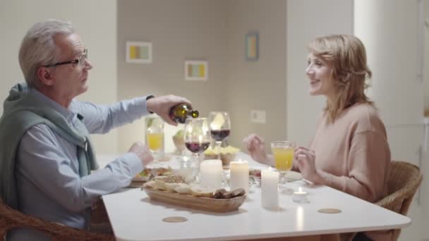 Zoom Senior Uomo Versando Vino Rosso Bicchieri Parlando Con Moglie — Video Stock