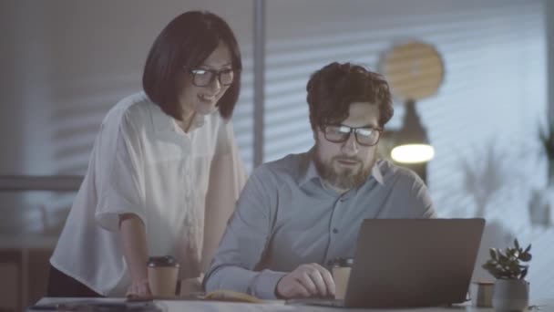 미디엄은 아시아 사업가가 안경을 웃으면서 사무실에서 노트북으로 일하는 동료와 일하는 — 비디오