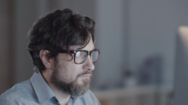 Ciddi bir iş adamının karanlık ofisinde masasında oturup bilgisayardaki işini bitirmesini.