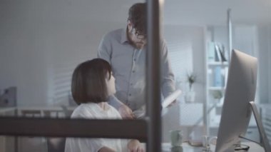 Dosyası olan sakallı bir adamın, bilgisayarla çalışan ve karanlık ofiste analitiği tartışan bir meslektaşının fotoğrafını çekiyorum.