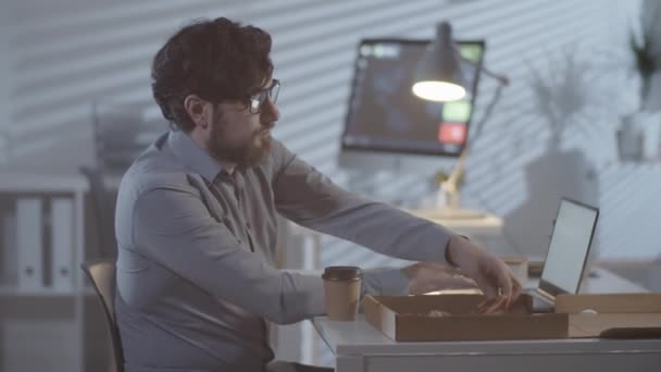 Tiro Medio Hombre Barbudo Gafas Sentado Escritorio Comiendo Pizza Mientras — Vídeos de Stock