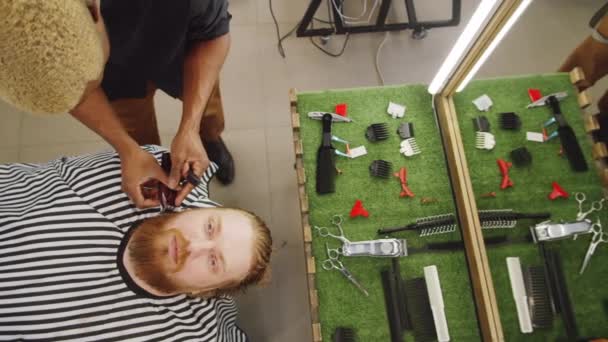 美籍黑人理发师在理发店给红头发白人男人修剪胡子的自上而下的镜头 — 图库视频影像