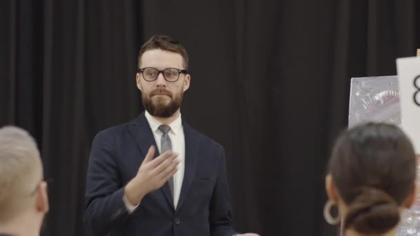 Professional Bearded Male Auctioneer Eyeglasses Formal Suit Pointing Bidding Paddles — Stock Video