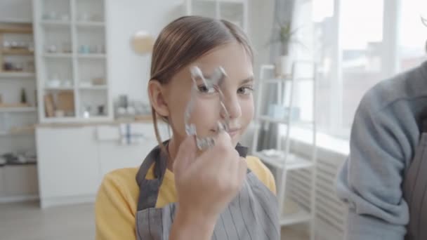 幸せな11歳の女の子を通して見て金属ウサギのクッキーカッターと笑顔でカメラで準備しながらイースターのためにおばあちゃんでキッチン — ストック動画