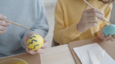 Paskalya süslemeleri yaparken, fırçalarla fırça çeken büyükanne ve torunlarının yüksek açılı yakın çekimleri.