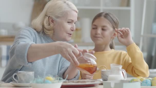 Senior Woman Pouring Tea Cups Talking Little Granddaughter Earing Rabbit — Stock Video